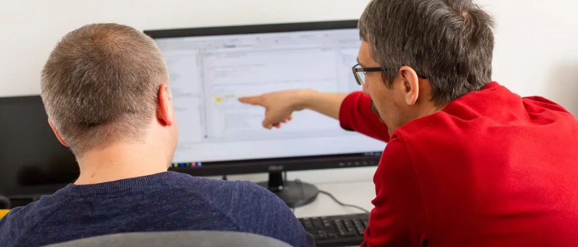 two software developers discussing in front of a monitor